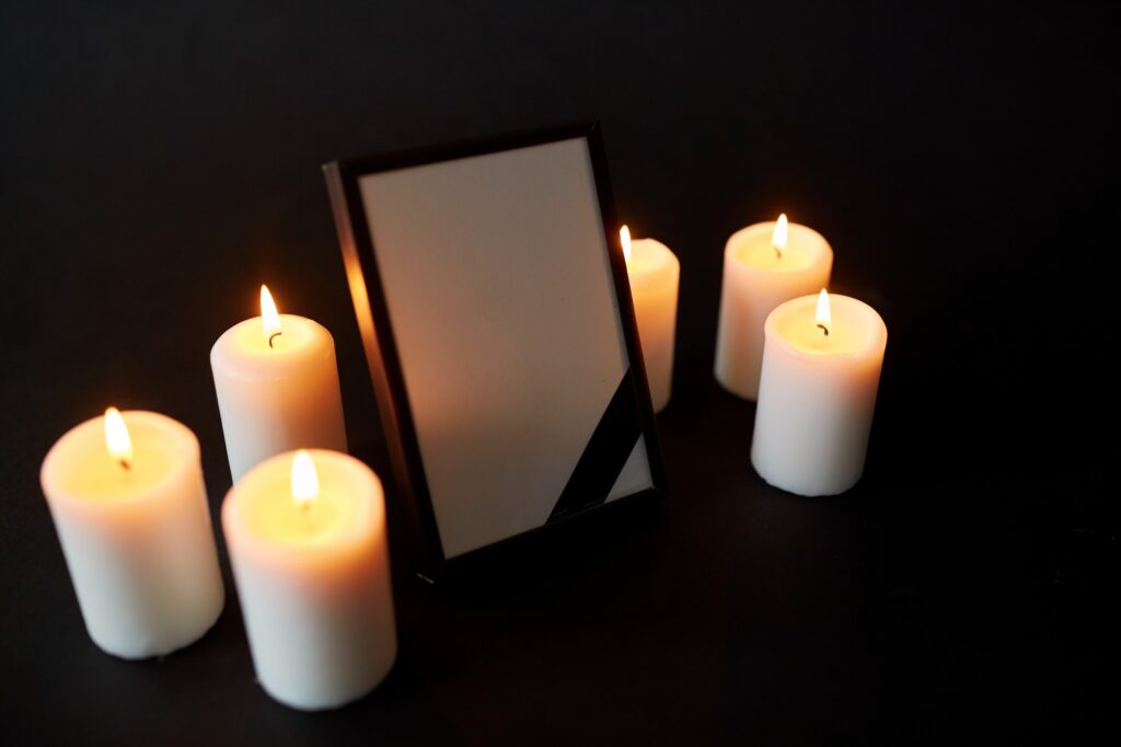 photo frame with black mourning ribbon and candles