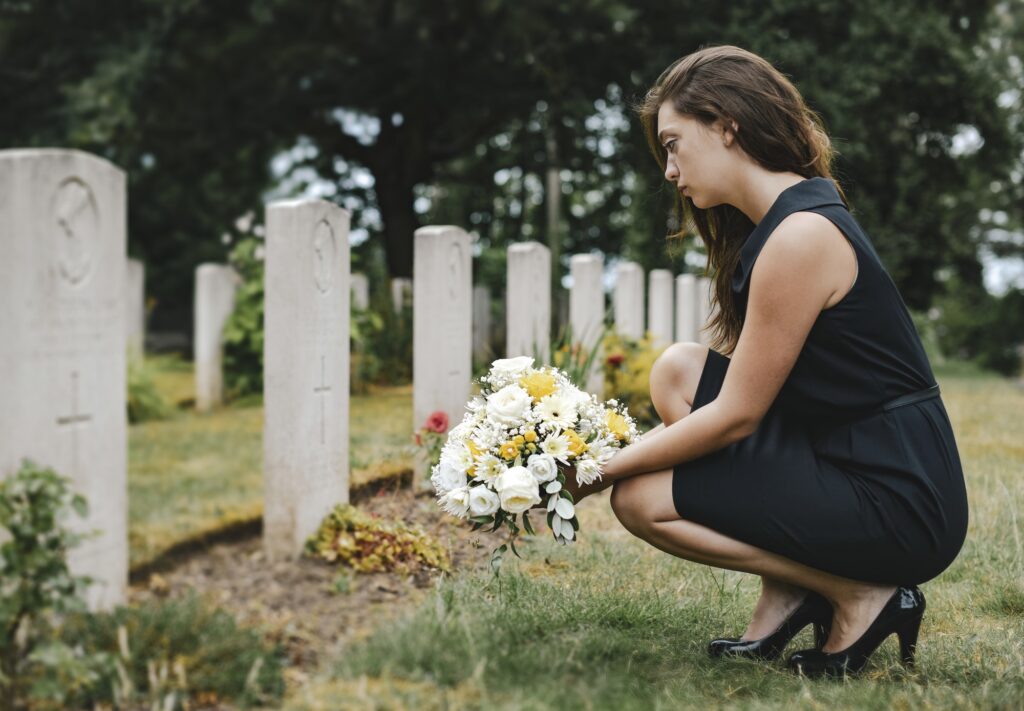 Young widow laying flowers at the grave